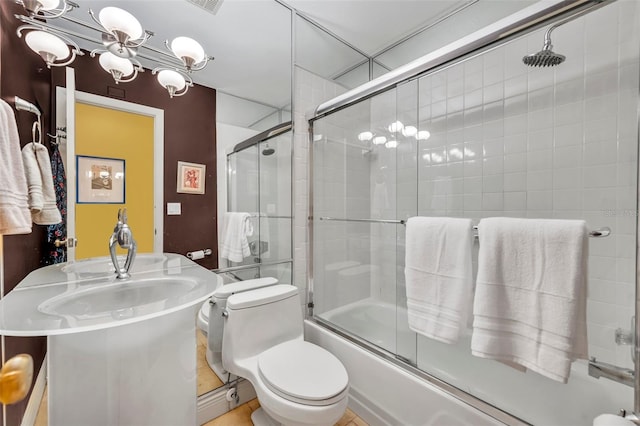 full bath with a sink, a notable chandelier, toilet, and enclosed tub / shower combo