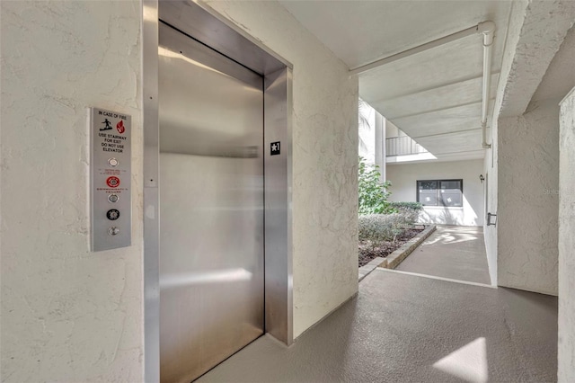 interior space featuring elevator and a textured wall