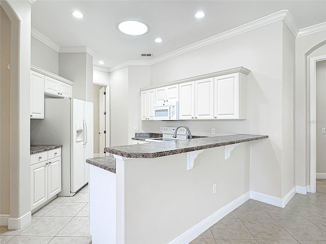 kitchen with dark countertops, white appliances, crown molding, and a peninsula