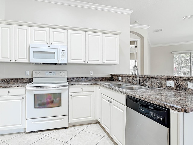 kitchen with white appliances, dark countertops, ornamental molding, a sink, and light tile patterned flooring