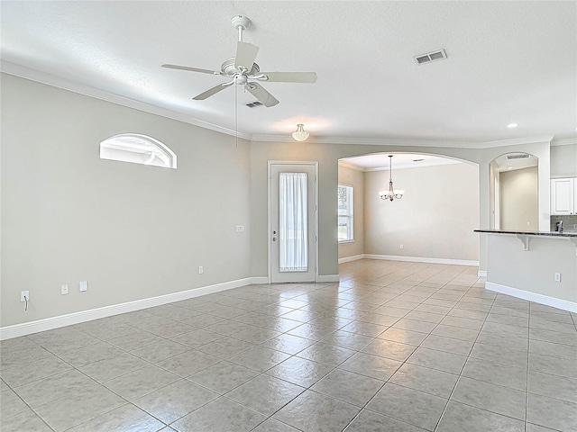 spare room with arched walkways, crown molding, light tile patterned flooring, baseboards, and ceiling fan with notable chandelier