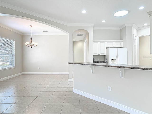 kitchen with white fridge with ice dispenser, crown molding, a kitchen breakfast bar, and light tile patterned floors