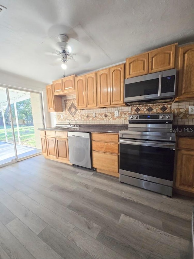 kitchen with stainless steel appliances, tasteful backsplash, wood finished floors, and a ceiling fan