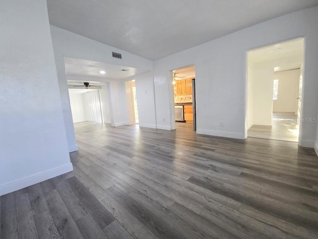 empty room with dark wood-style flooring, visible vents, ceiling fan, and baseboards