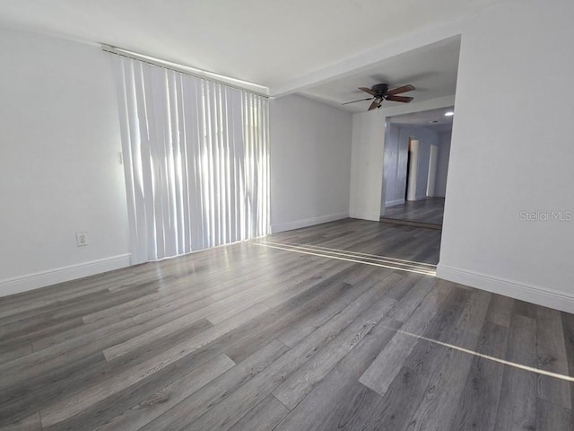 empty room featuring ceiling fan, baseboards, and wood finished floors