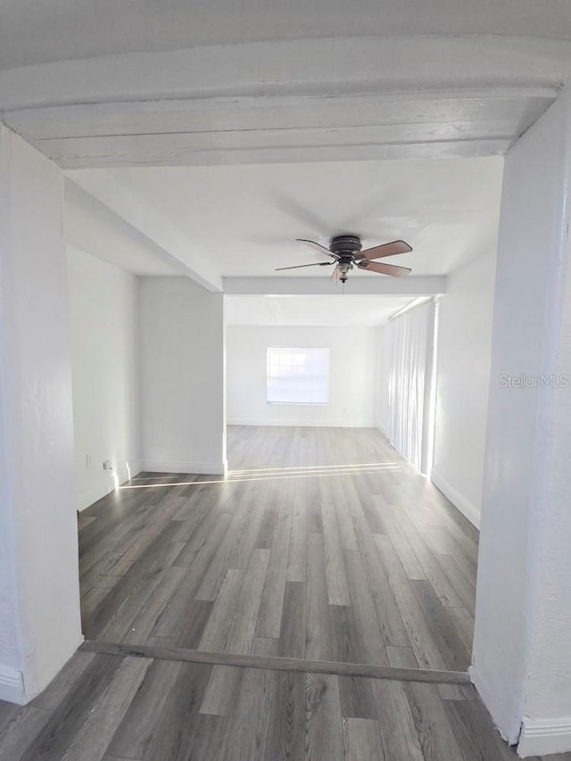 spare room featuring a ceiling fan, baseboards, and wood finished floors