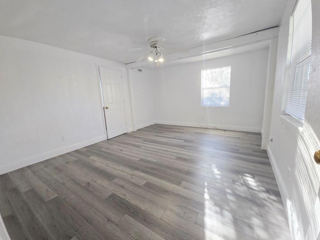 empty room featuring ceiling fan, baseboards, and wood finished floors