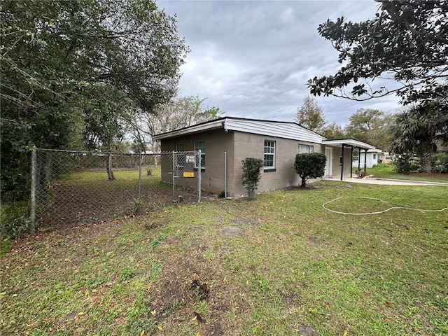 exterior space featuring a lawn, concrete block siding, fence, and a carport