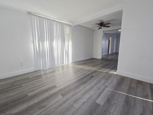 unfurnished room with baseboards, a ceiling fan, and wood finished floors