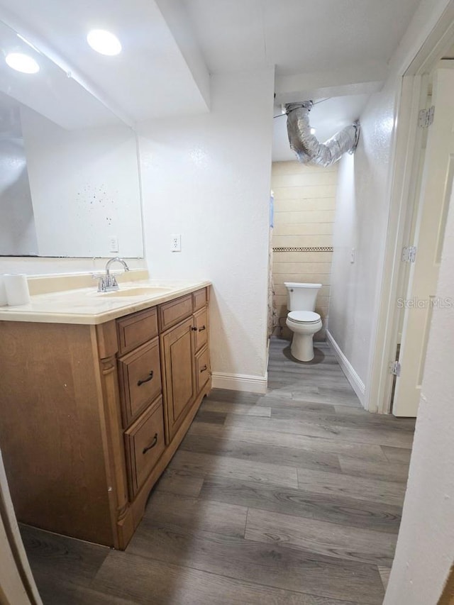 bathroom featuring baseboards, vanity, toilet, and wood finished floors