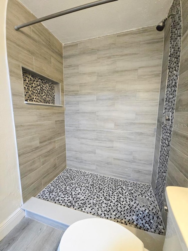 bathroom with baseboards, a stall shower, and toilet
