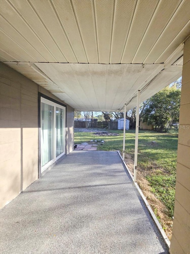 view of patio / terrace with an outdoor structure, fence, and a shed
