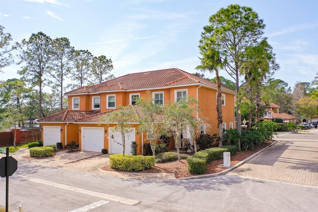 mediterranean / spanish-style home featuring stucco siding, fence, concrete driveway, and a tiled roof