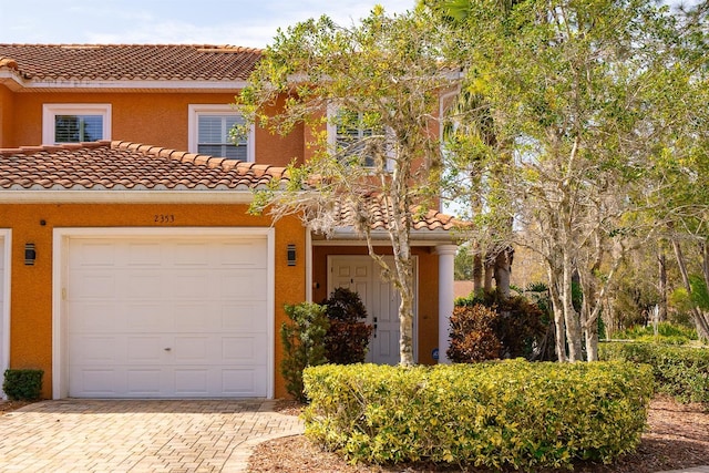 view of front of property with a garage, a tiled roof, decorative driveway, and stucco siding