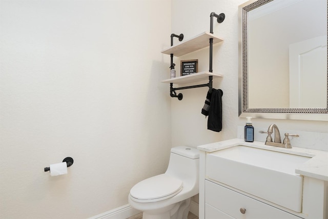 half bath with vanity, toilet, and baseboards