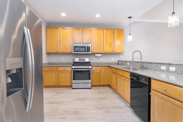 kitchen featuring light wood-style flooring, appliances with stainless steel finishes, light stone counters, decorative light fixtures, and a sink