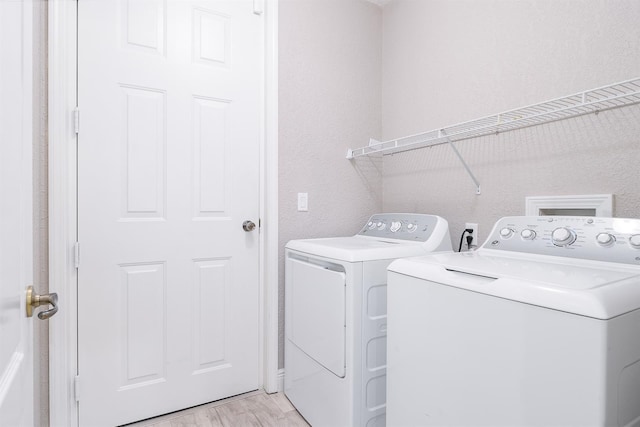 washroom with light wood-style floors, a textured wall, laundry area, and independent washer and dryer