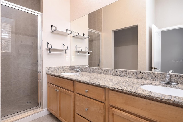 bathroom with double vanity, a shower stall, and a sink