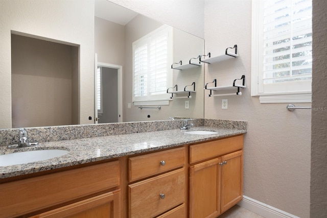 full bath with a textured wall, double vanity, and a sink