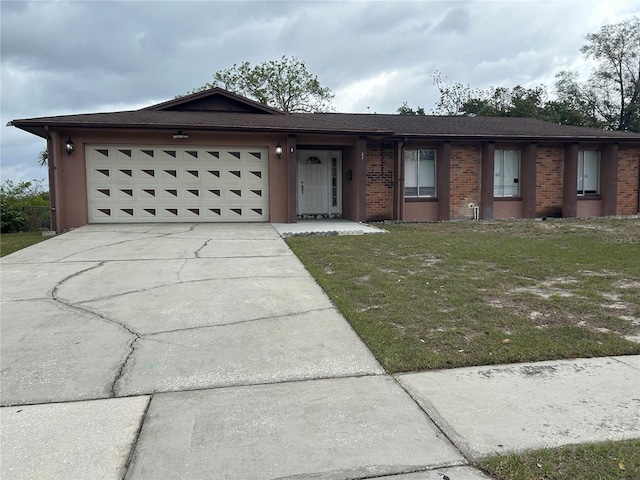 single story home with a garage, concrete driveway, brick siding, and a front yard