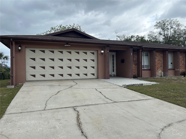 ranch-style home with a garage, brick siding, driveway, stucco siding, and a front lawn