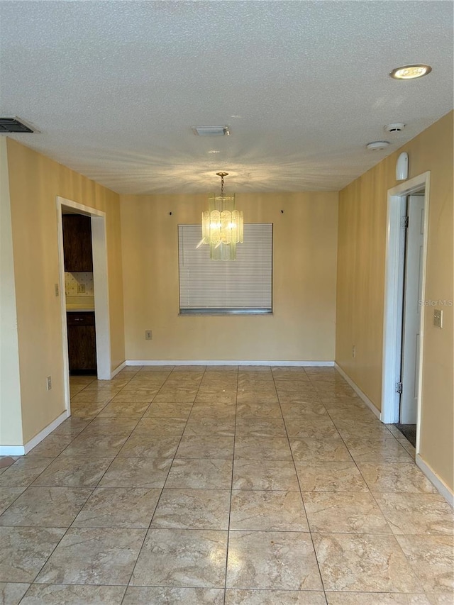 tiled spare room featuring visible vents, a textured ceiling, baseboards, and an inviting chandelier