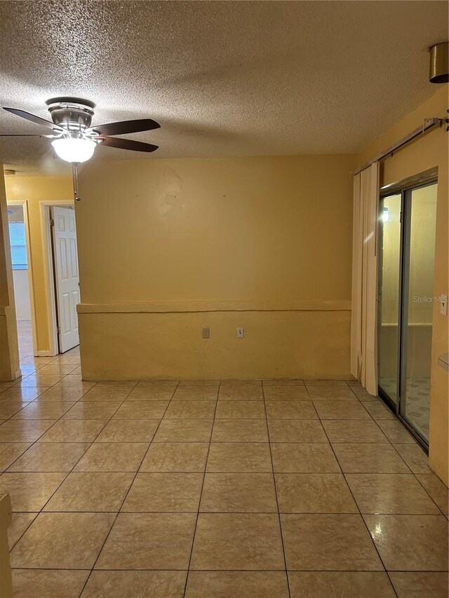 spare room featuring light tile patterned floors, ceiling fan, and a textured ceiling