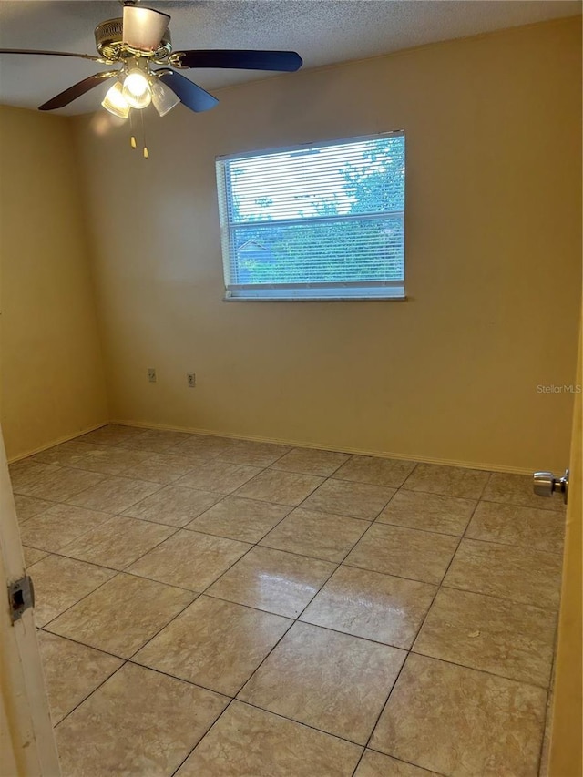 spare room featuring ceiling fan, a textured ceiling, and light tile patterned floors