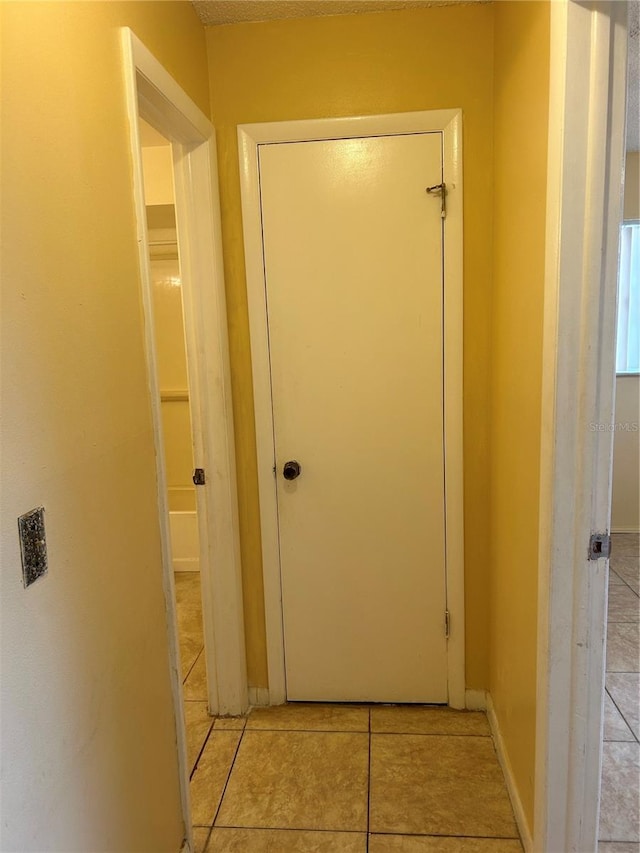 hallway with light tile patterned floors and baseboards