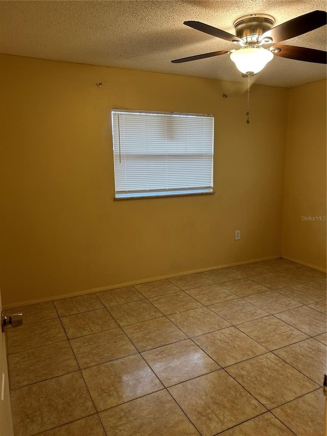 unfurnished room with light tile patterned floors, ceiling fan, baseboards, and a textured ceiling