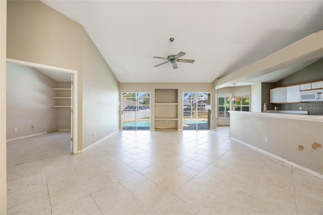 spare room featuring baseboards, built in shelves, lofted ceiling, and ceiling fan