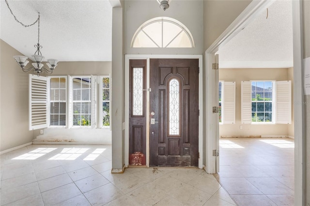 foyer with tile patterned floors, a notable chandelier, high vaulted ceiling, and a textured ceiling