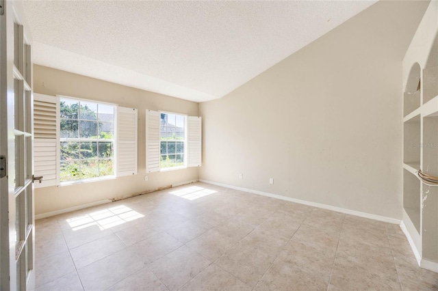 tiled spare room with lofted ceiling, baseboards, and a textured ceiling