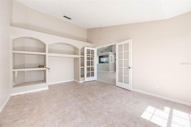 spare room with visible vents, built in shelves, baseboards, lofted ceiling, and french doors