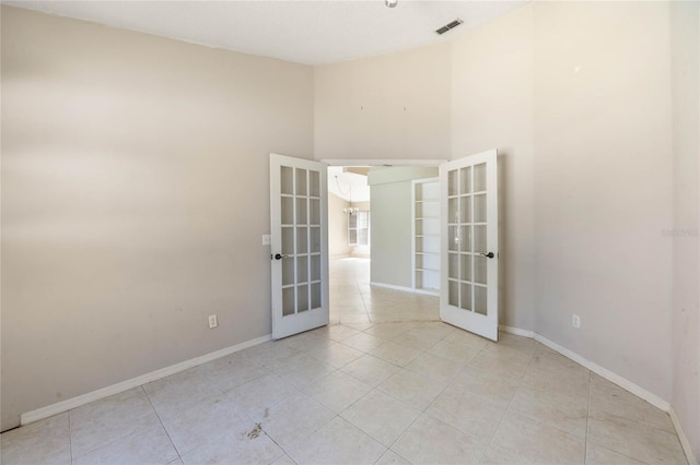 spare room featuring french doors, baseboards, visible vents, and light tile patterned flooring