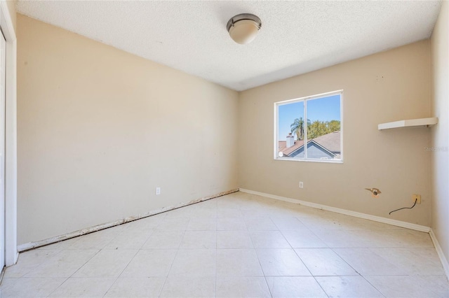 spare room featuring baseboards and a textured ceiling