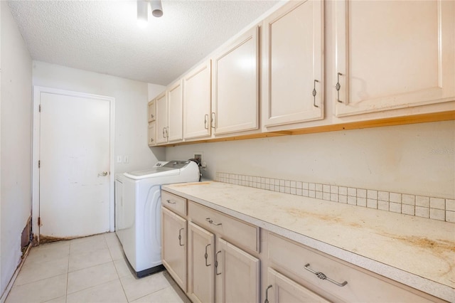 clothes washing area featuring light tile patterned floors, cabinet space, a textured ceiling, and separate washer and dryer