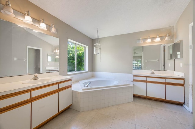 full bath with tile patterned floors, two vanities, a bath, and a sink