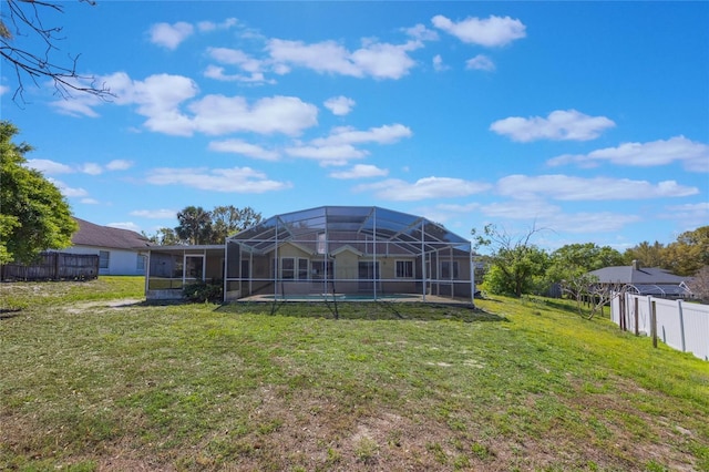 rear view of house featuring a lanai, a fenced in pool, a yard, and fence