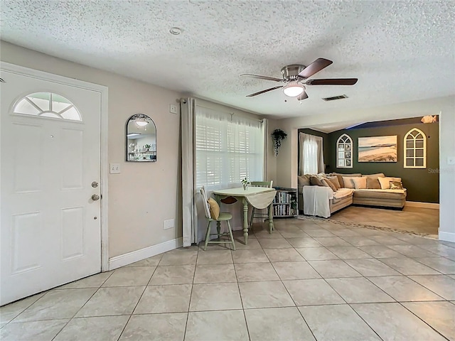 foyer entrance featuring light tile patterned floors, baseboards, a ceiling fan, and a textured ceiling