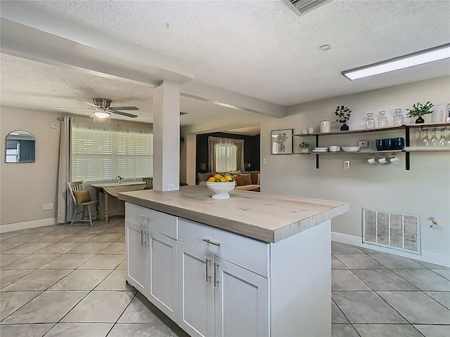 kitchen with light tile patterned floors, white cabinetry, visible vents, and a textured ceiling