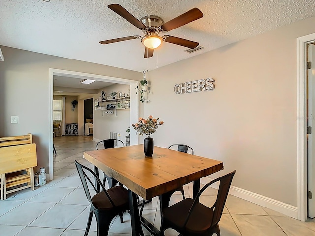 dining room with light tile patterned floors, ceiling fan, a textured ceiling, visible vents, and baseboards