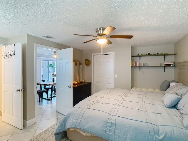 bedroom with light tile patterned floors, a textured ceiling, visible vents, and a ceiling fan