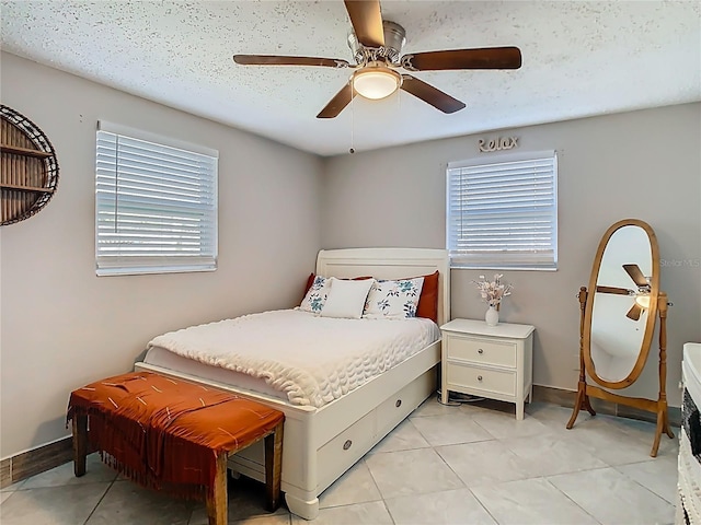 bedroom with light tile patterned floors, ceiling fan, baseboards, and a textured ceiling