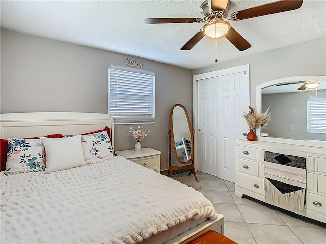 bedroom featuring a ceiling fan, light tile patterned flooring, and a textured ceiling