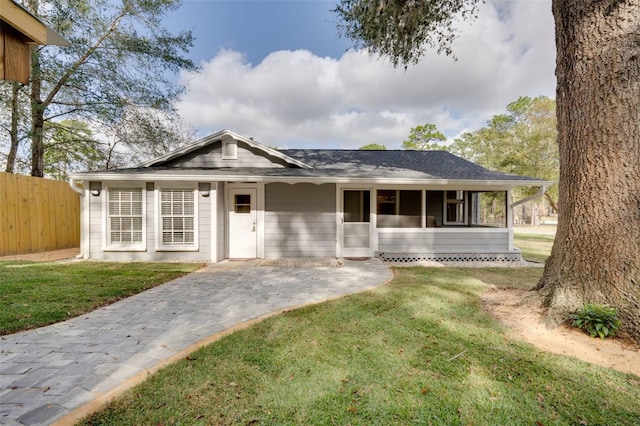 view of front facade with a sunroom, fence, and a front lawn