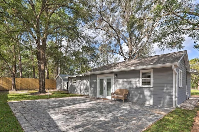 rear view of property featuring a patio area, fence, an outdoor structure, and french doors