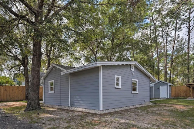 view of side of property with an outbuilding, fence, and a storage shed