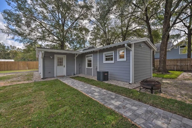 view of outdoor structure featuring an outdoor fire pit, fence, and cooling unit