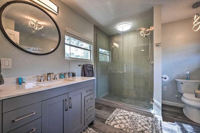 full bath featuring toilet, a stall shower, vanity, a textured ceiling, and wood finished floors